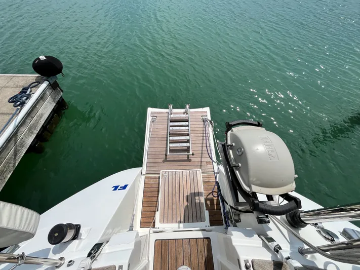 Lali Yacht Photos Pics Beneteau Oceanis 510 CU 1994 yacht stern with swim platform and ladder on calm water.