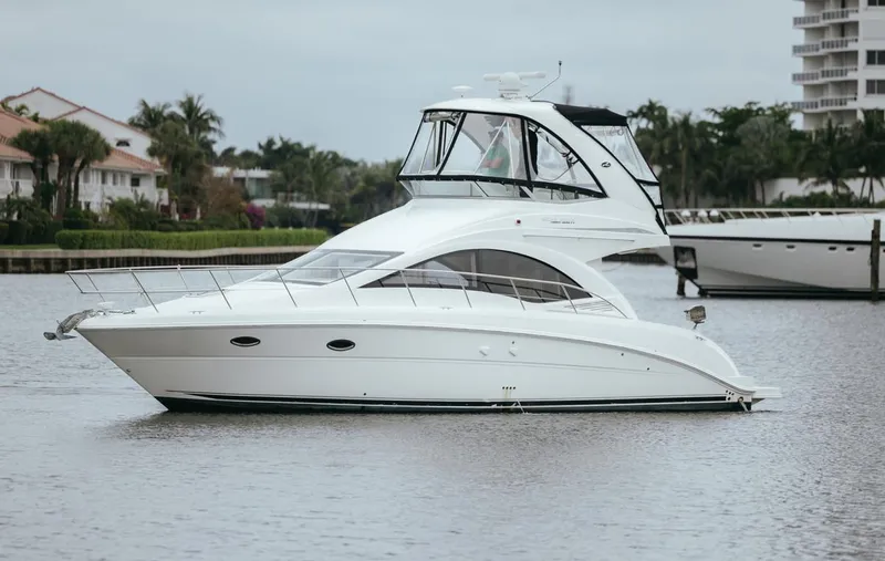  Yacht Photos Pics 2010 Sea Ray 390 Sedan Bridge yacht on calm water, surrounded by lush greenery.