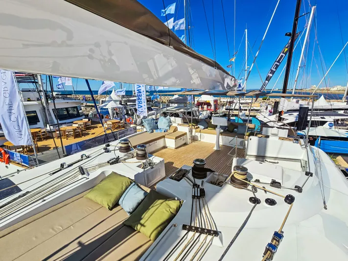 Firefly Yacht Photos Pics Luxurious 2012 Lagoon 620 NEO catamaran at a marina, showcasing spacious deck and seating.