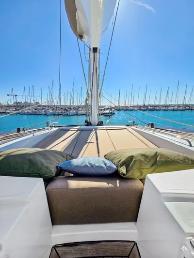 Firefly Yacht Photos Pics Luxurious Lagoon 620 NEO yacht deck with cushions, overlooking marina, sunny day.
