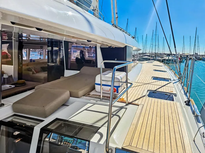 Firefly Yacht Photos Pics Luxurious Lagoon 620 NEO yacht deck with sun loungers, docked in a marina, 2012 model.