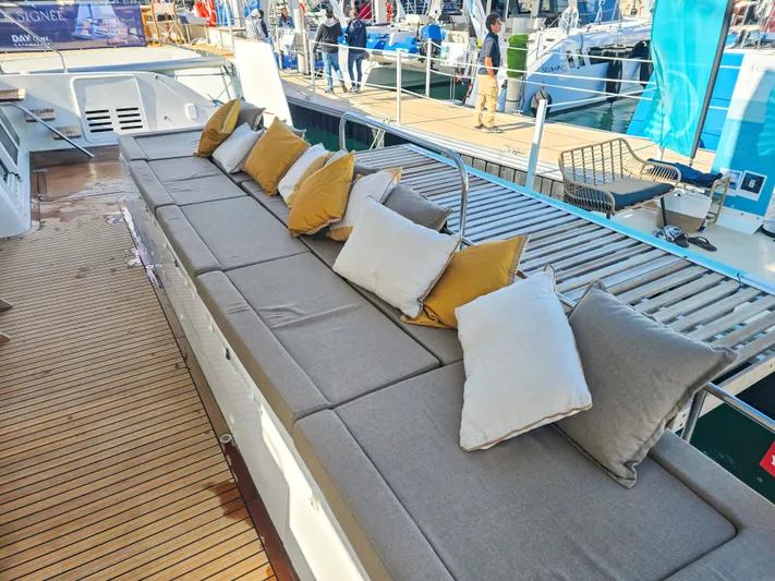 Firefly Yacht Photos Pics Luxurious seating area on 2012 Lagoon 620 NEO yacht with cushions and wooden deck.