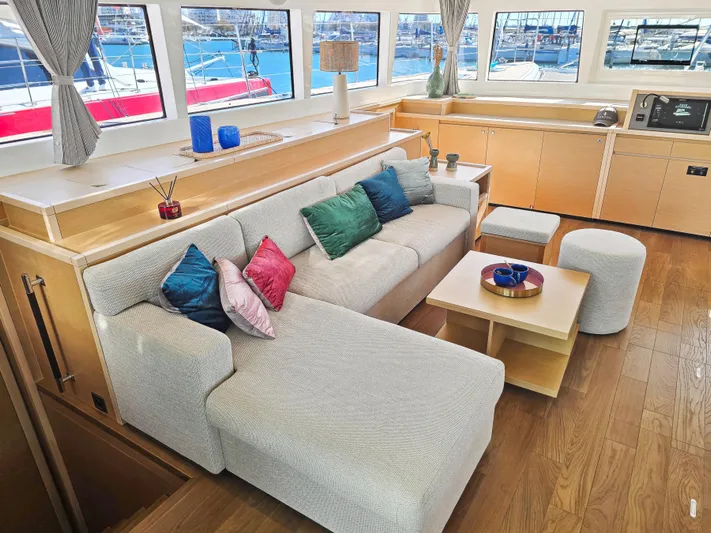 Firefly Yacht Photos Pics Luxurious interior of 2012 Lagoon 620 NEO yacht with modern furnishings and colorful cushions.