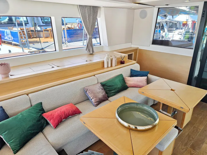 Firefly Yacht Photos Pics Luxurious interior of 2012 Lagoon 620 NEO yacht with cozy seating and colorful cushions.
