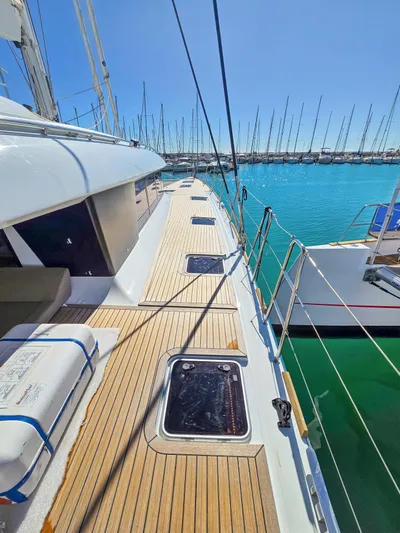 Firefly Yacht Photos Pics Lagoon 620 NEO 2012 yacht deck with teak flooring, docked in a marina under clear blue skies.