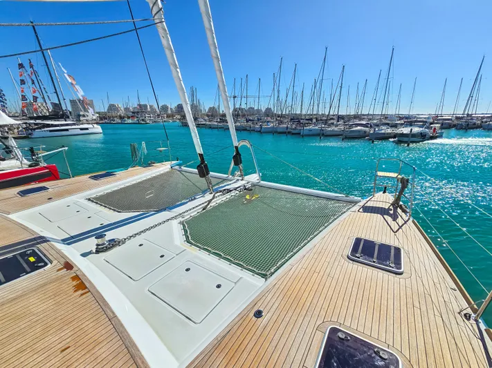 Firefly Yacht Photos Pics Lagoon 620 NEO 2012 catamaran docked in a marina with clear blue water.