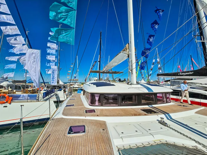 Firefly Yacht Photos Pics Lagoon 620 NEO 2012 catamaran at a marina, surrounded by flags and other boats.
