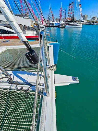 Firefly Yacht Photos Pics Lagoon 620 NEO 2012 catamaran docked at marina with vibrant flags and clear blue water.