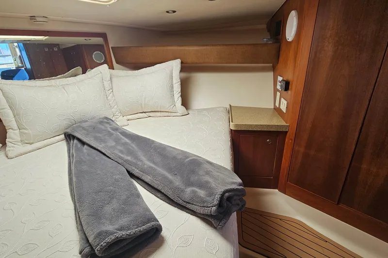  Yacht Photos Pics Cozy cabin interior of 2004 Luhrs 34 Convertible with plush bedding and wooden cabinetry.