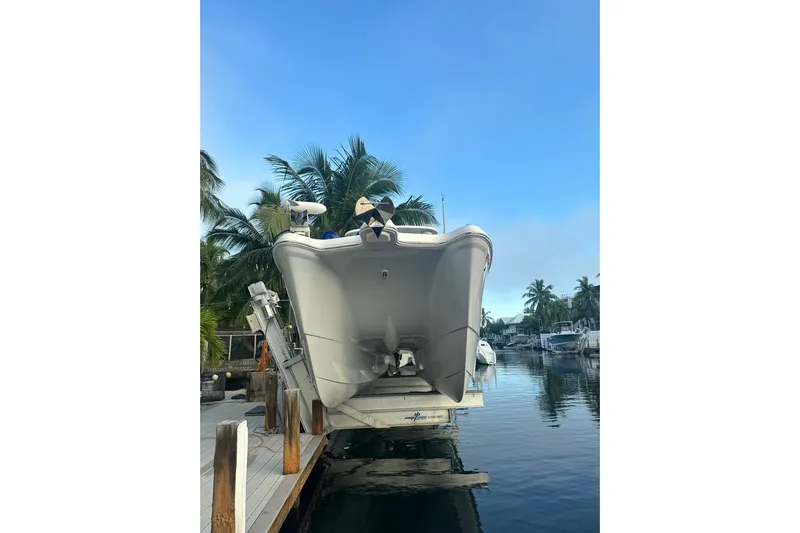  Yacht Photos Pics 2019 World Cat 295 CC boat on lift, surrounded by palm trees and calm water.