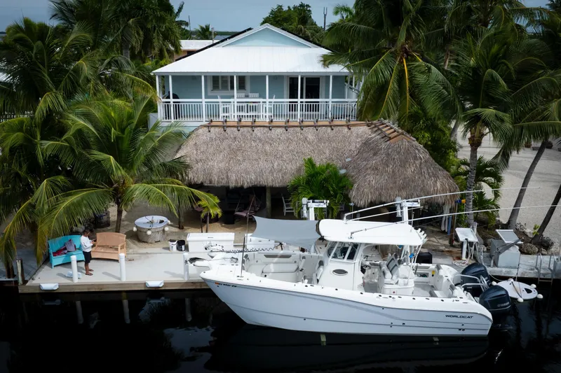  Yacht Photos Pics 2021 World Cat 295 CC boat docked by tropical house with palm trees.