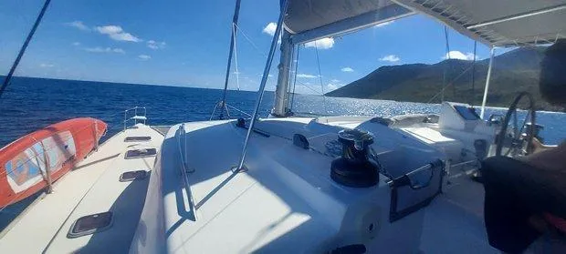 Katarina Yacht Photos Pics Lagoon 440 catamaran sailing on open sea, sunny day, mountainous coastline in background.