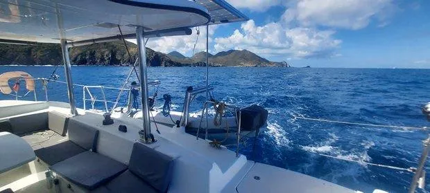 Katarina Yacht Photos Pics Lagoon 440 catamaran sailing near scenic coastline under blue skies, 2010 model.