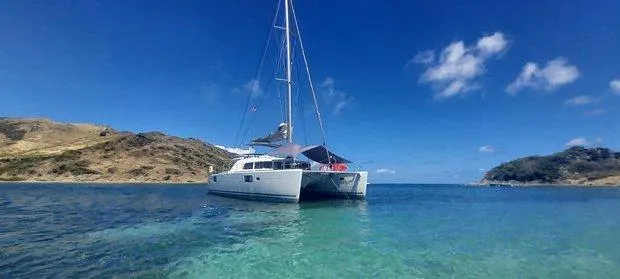 Katarina Yacht Photos Pics 2010 Lagoon 440 catamaran anchored in clear turquoise waters, surrounded by scenic hills.