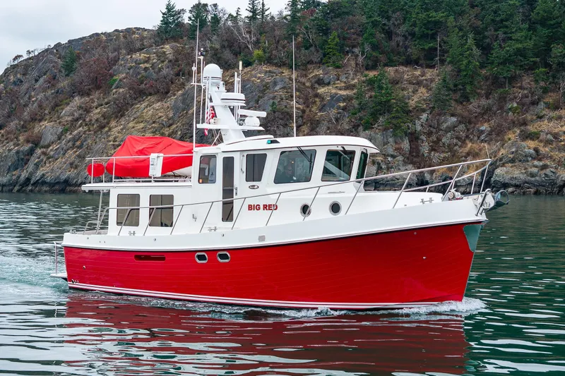 Big Red Yacht Photos Pics 2007 American Tug 41 boat with red hull cruising near rocky shoreline.