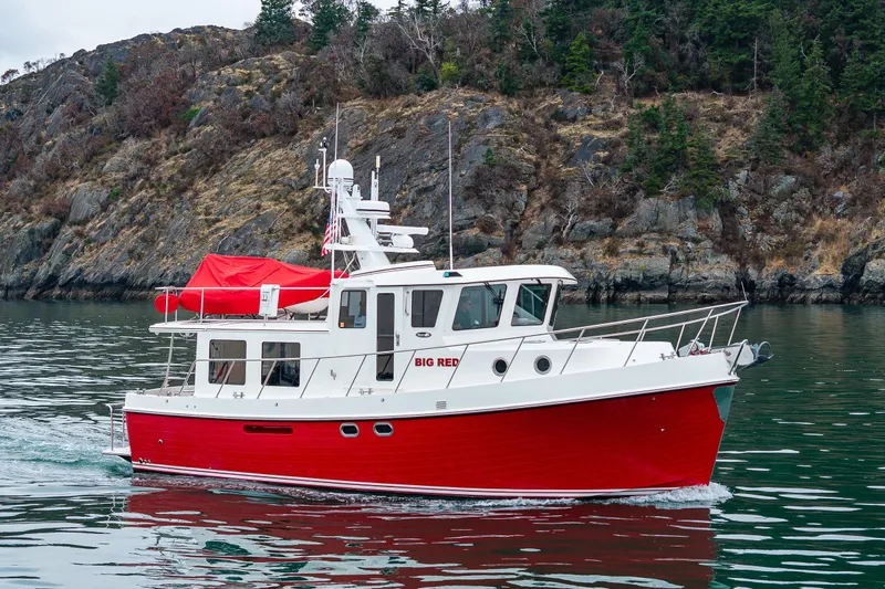 Big Red Yacht Photos Pics Red 2007 American Tug 41 cruising near rocky shoreline with trees.