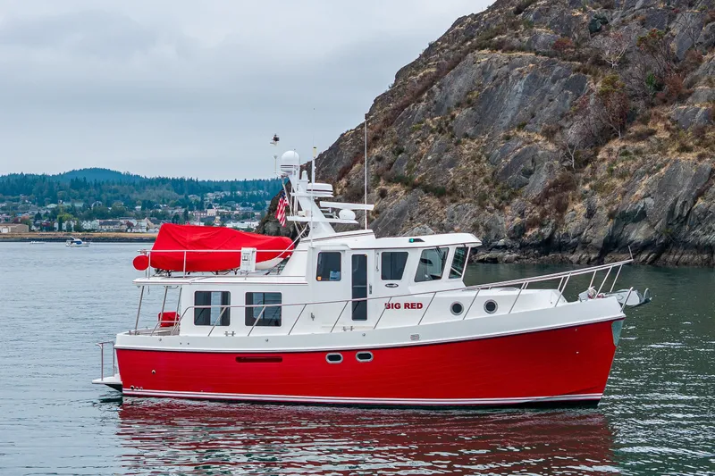 Big Red Yacht Photos Pics Red 2007 American Tug 41 boat cruising near rocky shoreline.