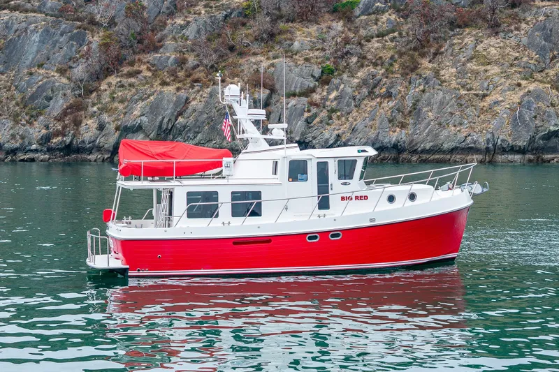 Big Red Yacht Photos Pics Red 2007 American Tug 41 boat on calm water near rocky shoreline.