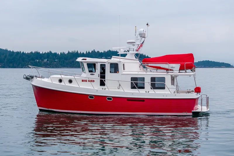Big Red Yacht Photos Pics Red and white 2007 American Tug 41 boat on calm water, forested shoreline in background.