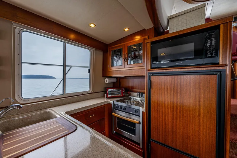 Big Red Yacht Photos Pics Luxurious 2007 American Tug 41 yacht kitchen with wood cabinetry, stove, and ocean view.