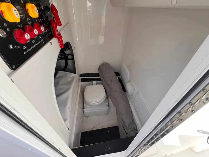  Yacht Photos Pics 2023 Fountain 38 Tournament Edition boat interior with control panel and compact toilet.