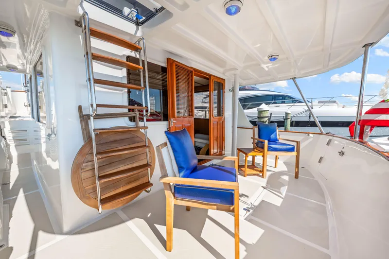 Sugar Yacht Photos Pics 2008 DeFever 52 Euro yacht deck with blue-cushioned chairs and wooden ladder.