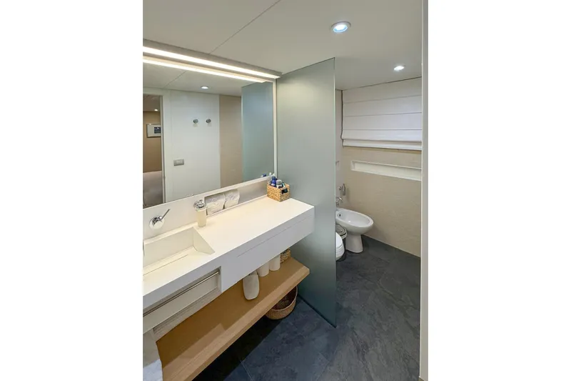  Yacht Photos Pics Modern yacht bathroom with sleek design, featuring a white sink, frosted glass partition, and elegant fixtures.