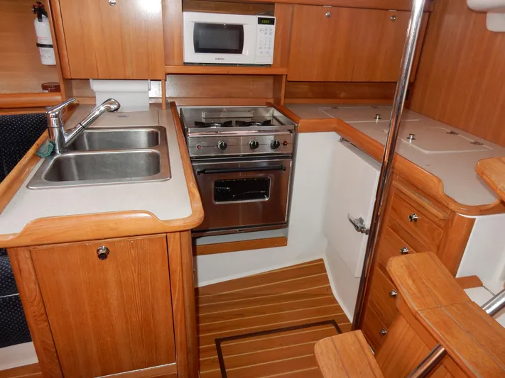Milky Way Yacht Photos Pics 2004 Catalina 350 yacht kitchen with wood cabinetry, dual sink, stove, and microwave.