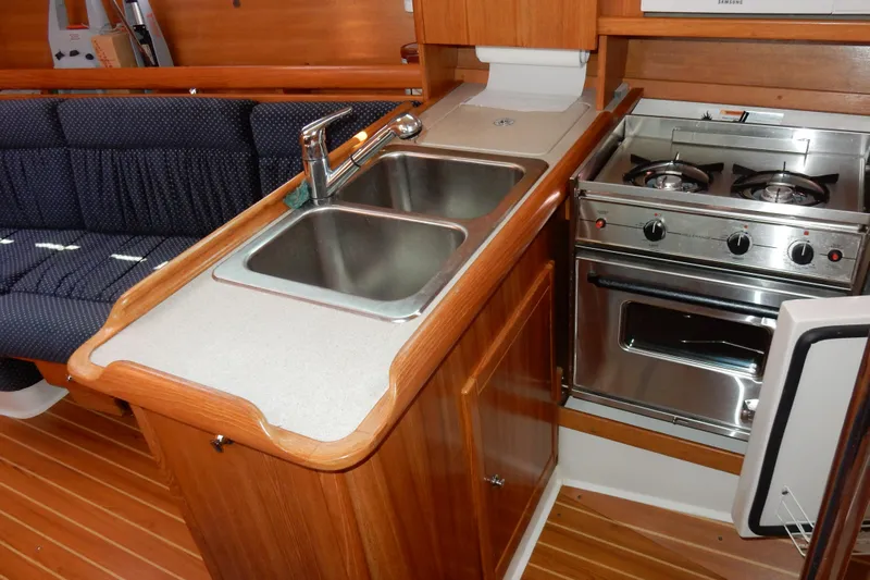 Milky Way Yacht Photos Pics 2004 Catalina 350 yacht interior kitchen with dual sink, stove, and wooden cabinetry.