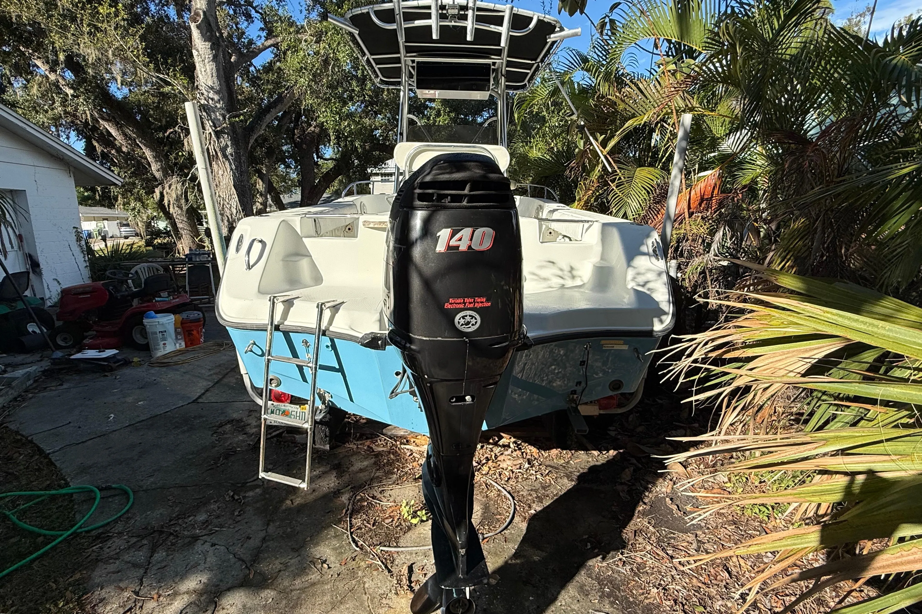 2002 Fishmaster 212 Travis Edition boat with 140 HP outboard motor in a garden setting.