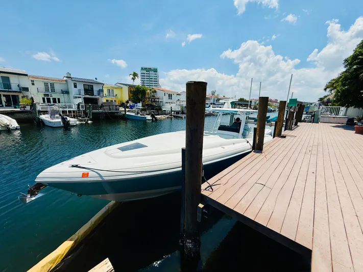  Yacht Photos Pics 2003 Intrepid 377 boat docked by waterfront homes under a sunny sky.