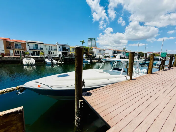  Yacht Photos Pics 2003 Intrepid 377 boat docked by waterfront homes under a clear blue sky.