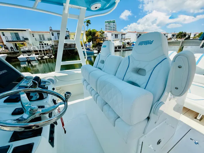  Yacht Photos Pics 2003 Intrepid 377 boat interior with white seating and steering wheel, docked near waterfront homes.
