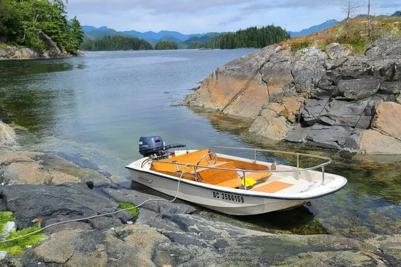  Yacht Photos Pics A small boat moored on rocky shore in scenic coastal landscape.