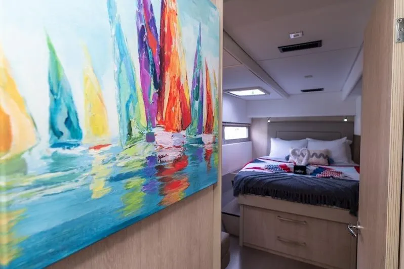 Ruby One Yacht Photos Pics Interior of 2020 Leopard 58 yacht with colorful sailboat painting and cozy bedroom.