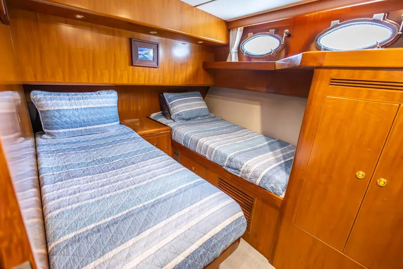 Bluewater Yacht Photos Pics Luxurious twin cabin in 2005 Ocean Alexander Raised Pilothouse yacht, featuring wood paneling and portholes.
