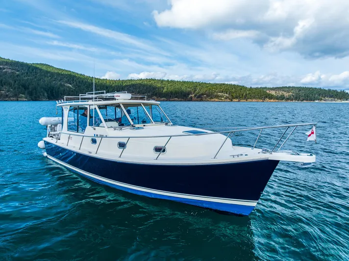Misty Yacht Photos Pics 2007 Mainship Pilot 34 boat on scenic blue water with forested shoreline.