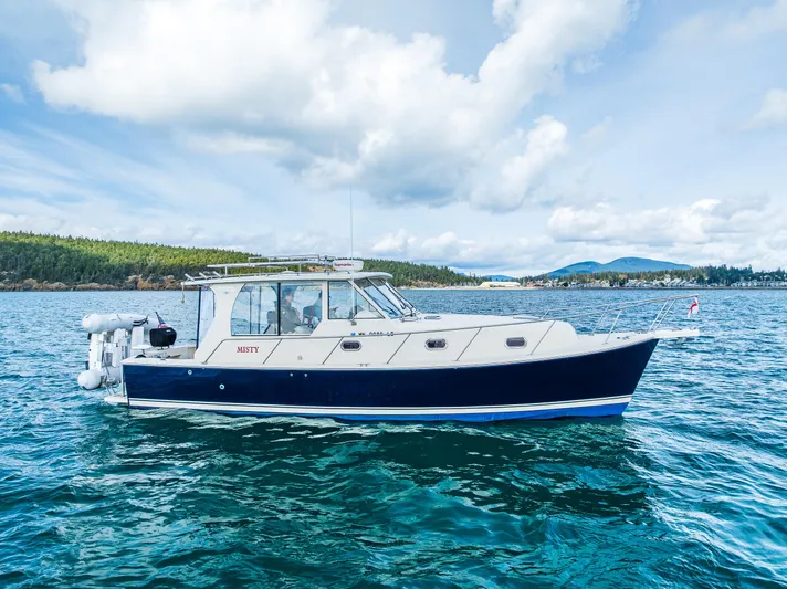 Misty Yacht Photos Pics 2007 Mainship Pilot 34 boat on calm water under a partly cloudy sky.