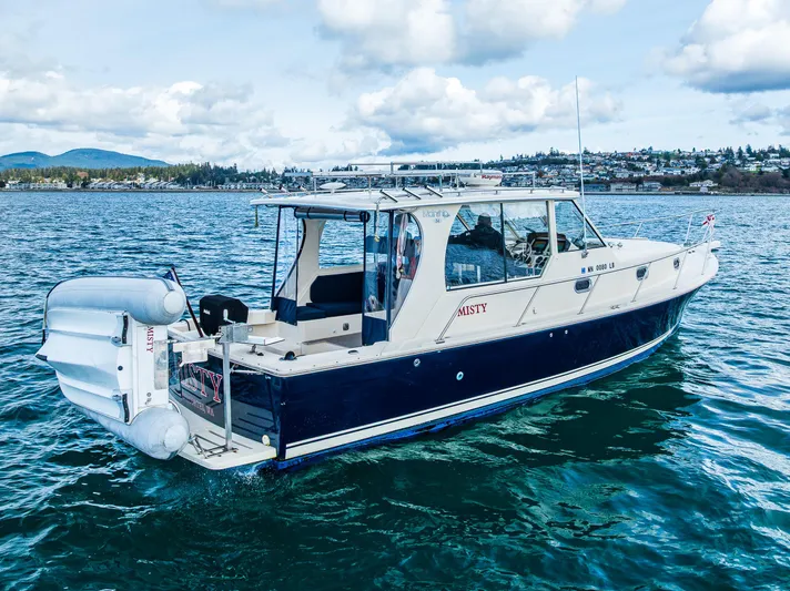 Misty Yacht Photos Pics 2007 Mainship Pilot 34 boat cruising on a scenic lake under a cloudy sky.