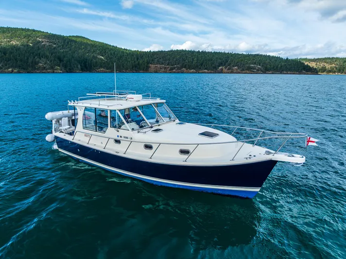 Misty Yacht Photos Pics 2007 Mainship Pilot 34 cruising on a scenic lake with forested hills in the background.