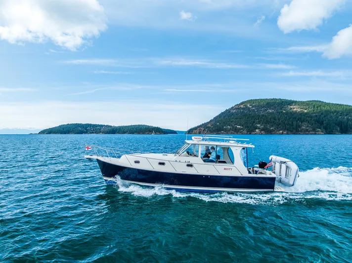 Misty Yacht Photos Pics 2007 Mainship Pilot 34 cruising on blue waters with scenic island backdrop.