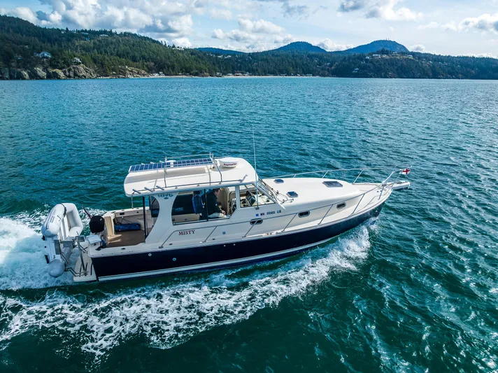 Misty Yacht Photos Pics 2007 Mainship Pilot 34 cruising on scenic blue waters with forested hills in the background.