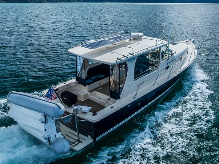 Misty Yacht Photos Pics 2007 Mainship Pilot 34 cruising on open water, rear view with dinghy attached.