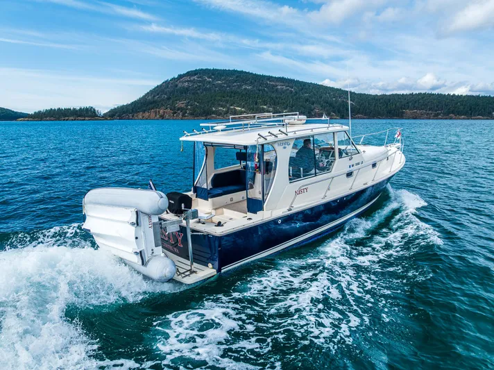 Misty Yacht Photos Pics 2007 Mainship Pilot 34 cruising on blue water near a scenic island backdrop.