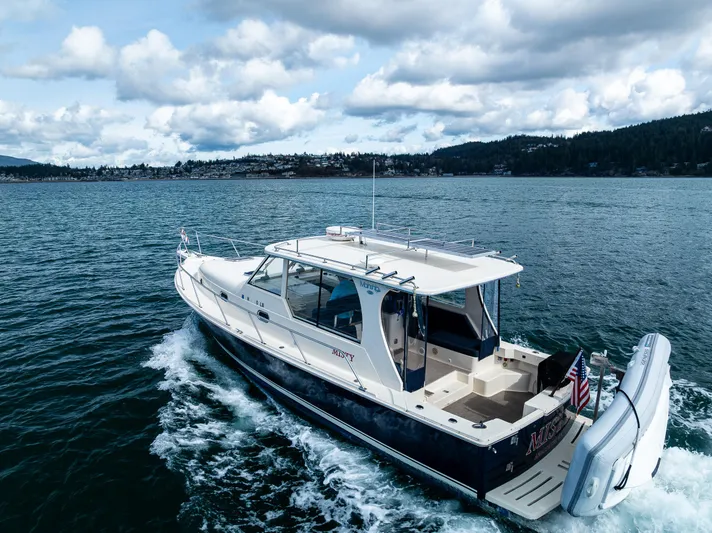 Misty Yacht Photos Pics 2007 Mainship Pilot 34 cruising on a scenic lake under a cloudy sky.