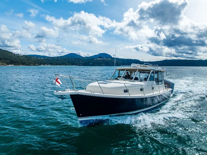 Misty Yacht Photos Pics 2007 Mainship Pilot 34 cruising on a scenic lake under a partly cloudy sky.