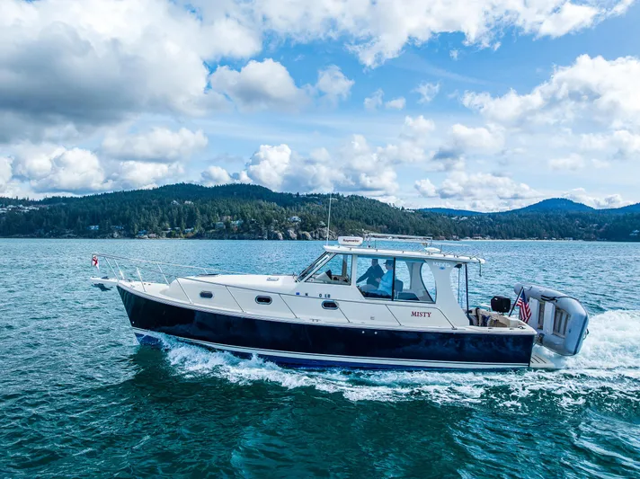 Misty Yacht Photos Pics 2007 Mainship Pilot 34 cruising on a scenic lake under a partly cloudy sky.