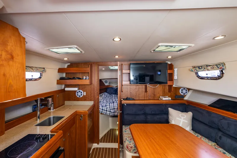 Misty Yacht Photos Pics 2007 Mainship Pilot 34 interior with wood finish, kitchenette, seating area, and cozy cabin.