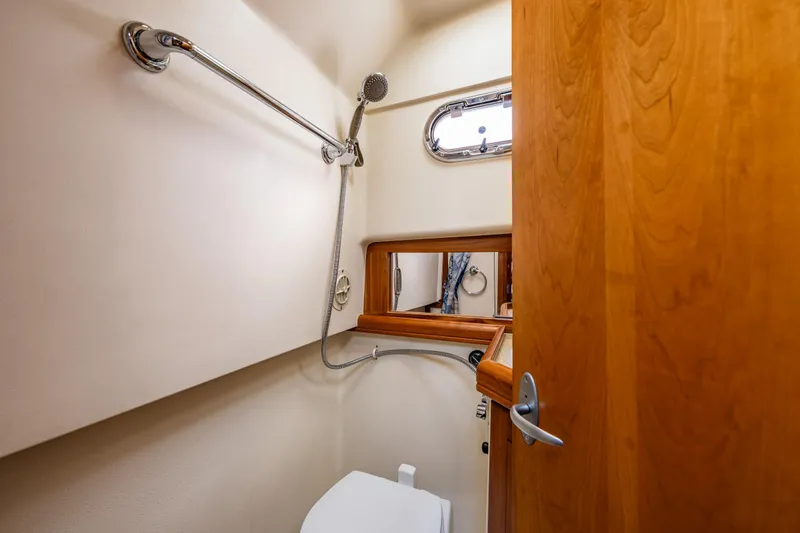 Misty Yacht Photos Pics 2007 Mainship Pilot 34 bathroom with shower, wooden door, and porthole window.