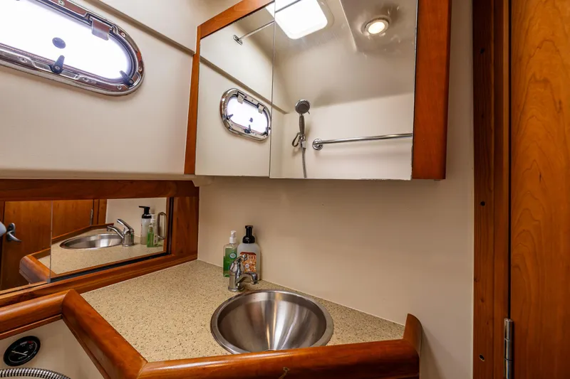 Misty Yacht Photos Pics 2007 Mainship Pilot 34 bathroom with sink, mirror, and porthole window.
